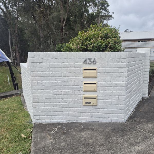 White-painted brick letterbox wall